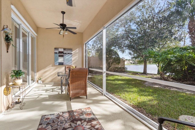 sunroom / solarium with a water view and ceiling fan