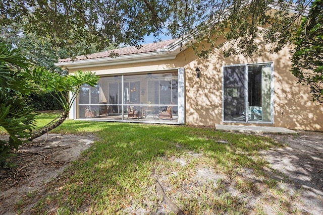 rear view of house featuring a patio, a lawn, and a sunroom