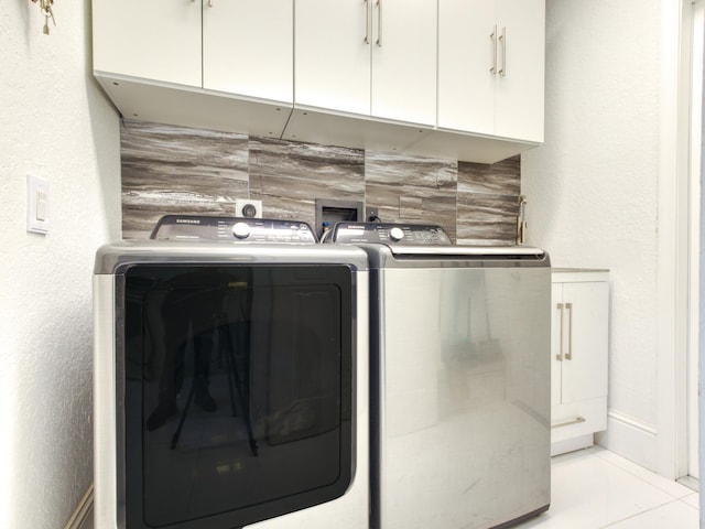 laundry area with separate washer and dryer, light tile patterned floors, and cabinets