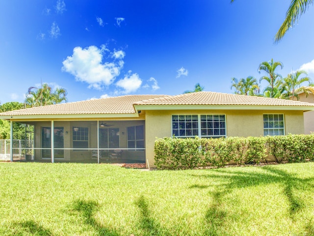 rear view of property featuring a lawn and a sunroom