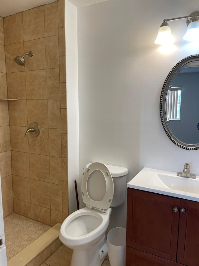 bathroom featuring vanity, toilet, tile patterned floors, and tiled shower