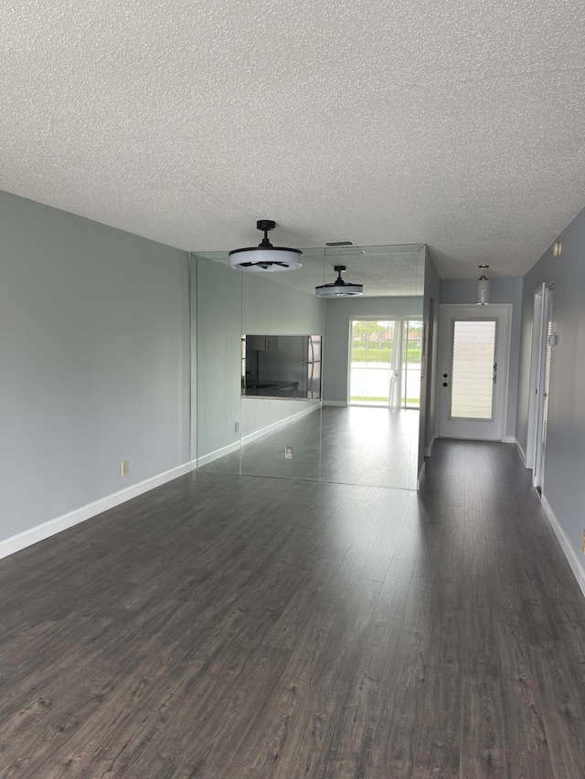 empty room with dark wood-type flooring, ceiling fan, and a textured ceiling