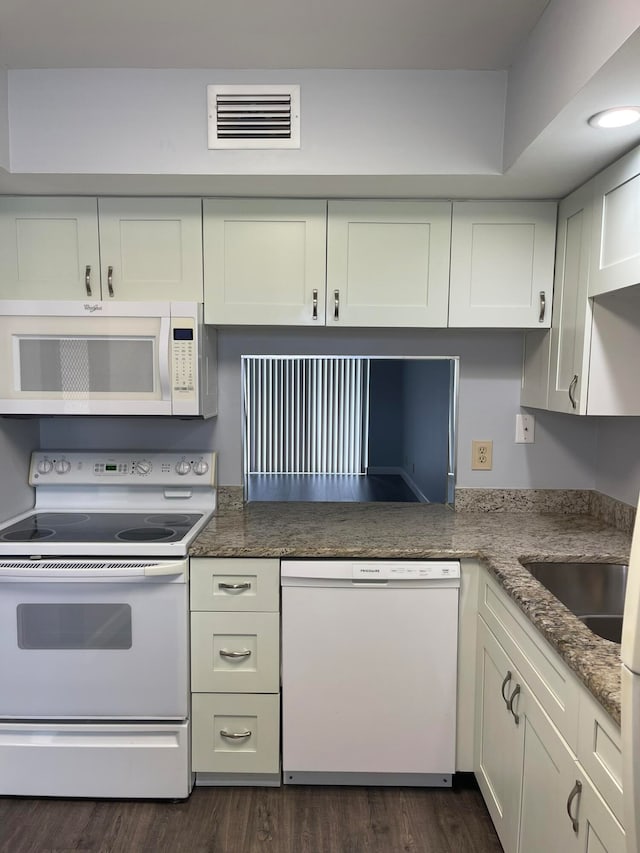 kitchen with dark wood-type flooring, white cabinetry, white appliances, and dark stone countertops