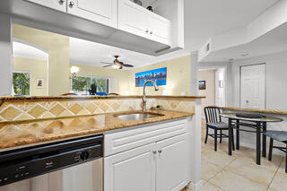 kitchen with light tile patterned floors, white cabinetry, stainless steel dishwasher, and sink