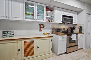 kitchen with white cabinets, appliances with stainless steel finishes, and light tile patterned flooring