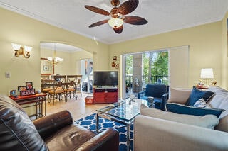 living room featuring crown molding and ceiling fan with notable chandelier