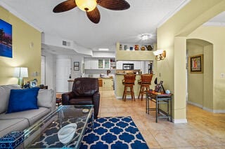 living room with tile patterned floors, ceiling fan, and crown molding