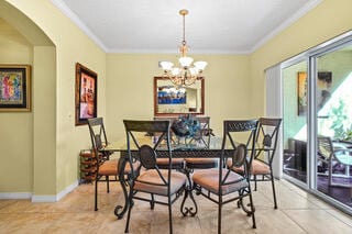 dining space with a chandelier, light tile patterned floors, and ornamental molding