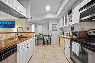 kitchen with white cabinets, light tile patterned flooring, sink, and stainless steel appliances