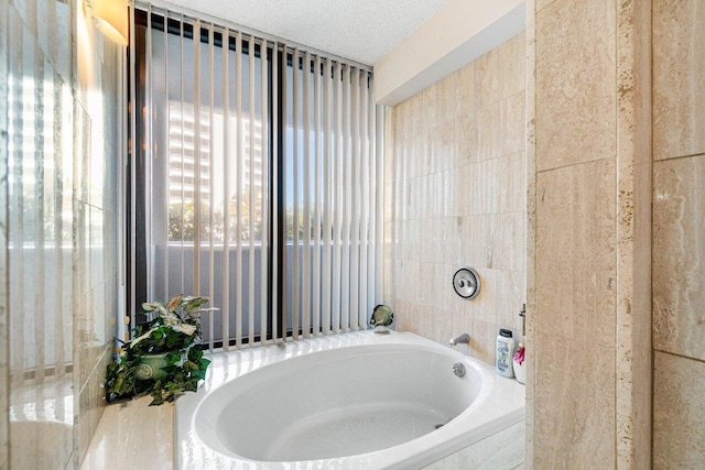 bathroom featuring a textured ceiling and tiled tub