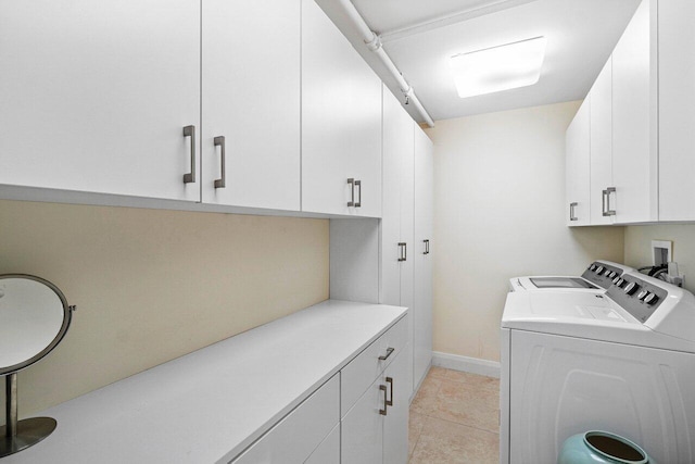 laundry room featuring washer and clothes dryer, cabinets, and light tile patterned floors