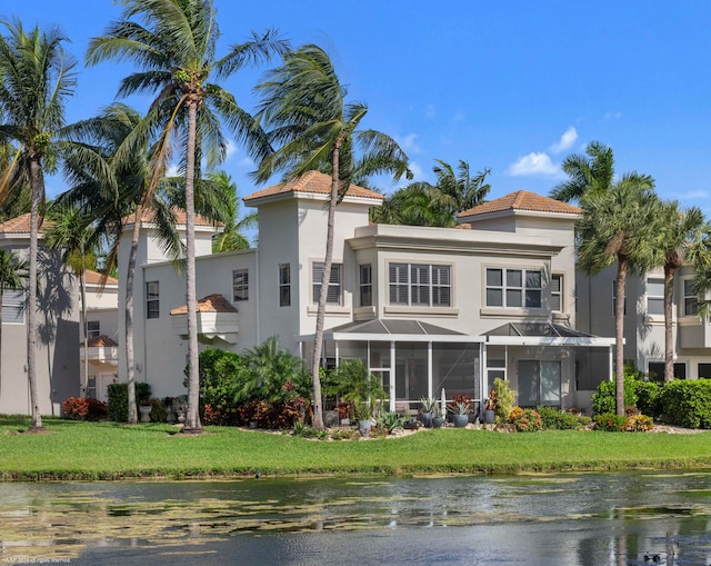 exterior space featuring a sunroom, a yard, and a water view