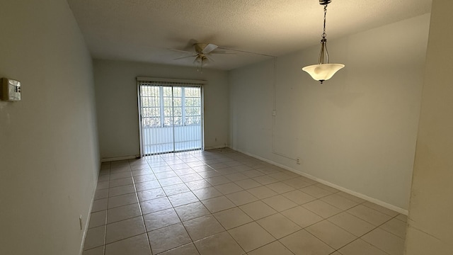 spare room with a textured ceiling, light tile patterned floors, a ceiling fan, and baseboards