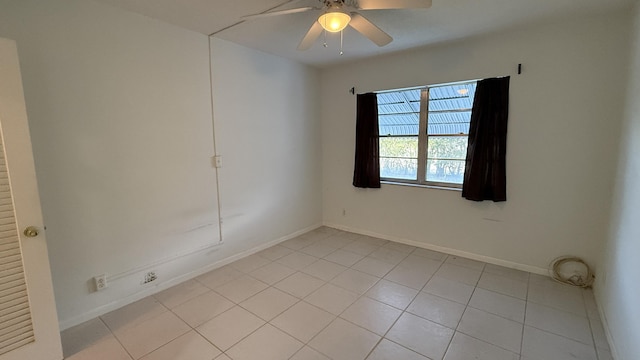 spare room with ceiling fan, light tile patterned flooring, and baseboards