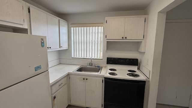 kitchen featuring a sink, light countertops, range with electric stovetop, and freestanding refrigerator