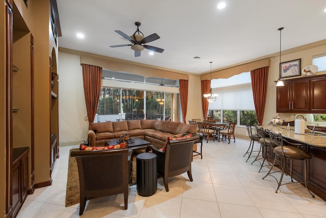 living room with ornamental molding, ceiling fan with notable chandelier, and light tile patterned floors