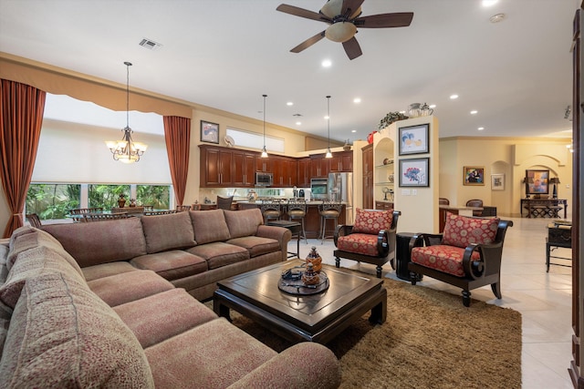 tiled living room featuring ceiling fan with notable chandelier and crown molding