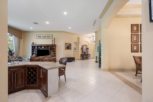 interior space with ornamental molding, light stone counters, a chandelier, and decorative light fixtures