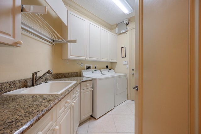 washroom featuring cabinets, sink, a textured ceiling, light tile patterned floors, and washer and clothes dryer