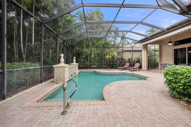 view of pool with glass enclosure, ceiling fan, and a patio