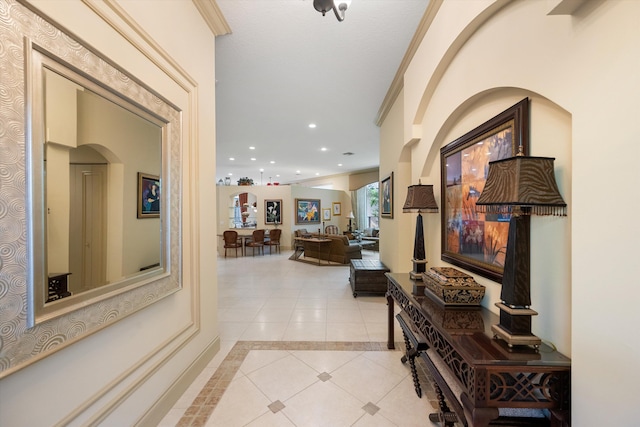 hall featuring light tile patterned floors and crown molding