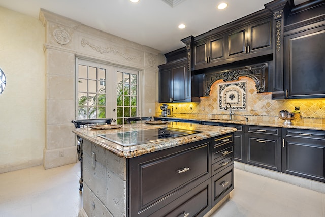 kitchen with black electric cooktop, a center island, sink, and light stone counters