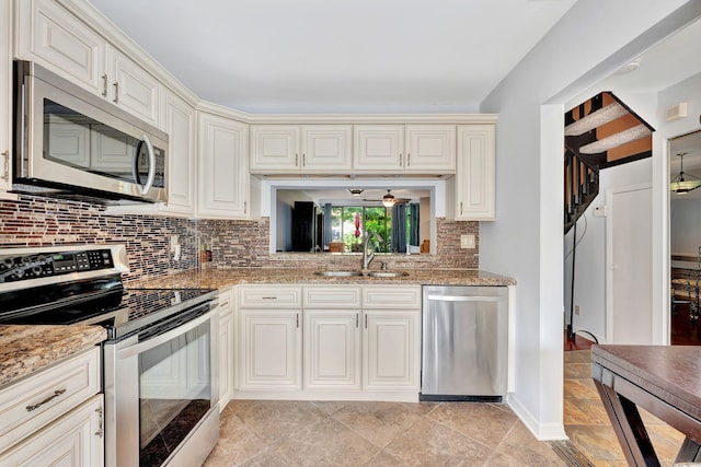 kitchen featuring stainless steel appliances, backsplash, light tile patterned floors, light stone countertops, and sink