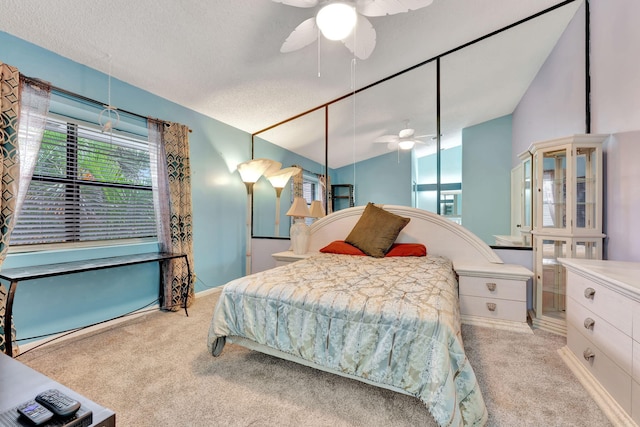 carpeted bedroom with vaulted ceiling, ceiling fan, and a textured ceiling