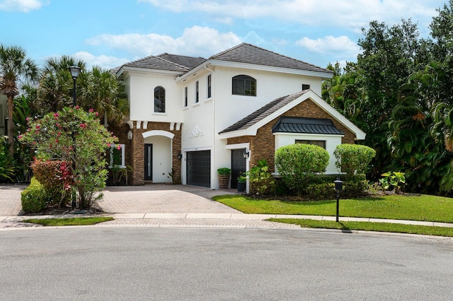 mediterranean / spanish house featuring a garage and a front yard