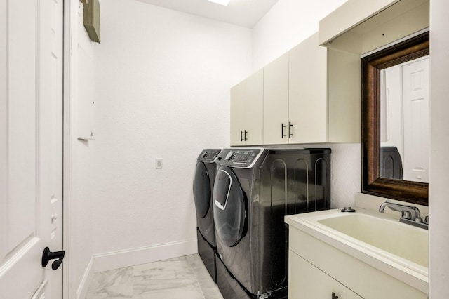 clothes washing area featuring washing machine and clothes dryer, cabinets, and sink