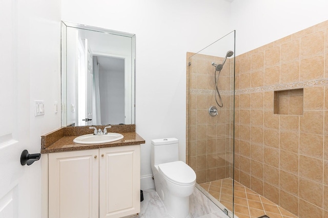 bathroom with toilet, vanity, and tiled shower