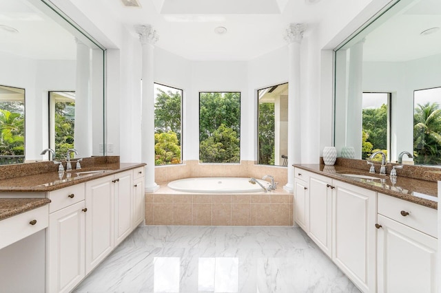 bathroom featuring vanity, a healthy amount of sunlight, and tiled tub