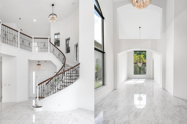 entrance foyer featuring a chandelier, a healthy amount of sunlight, and a towering ceiling