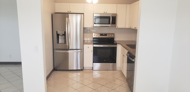 kitchen featuring tasteful backsplash, appliances with stainless steel finishes, light tile patterned floors, and white cabinets