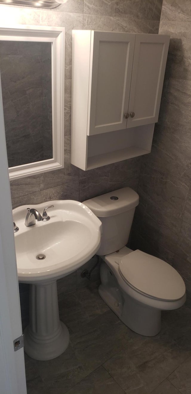 bathroom with toilet, tile walls, and tile patterned floors