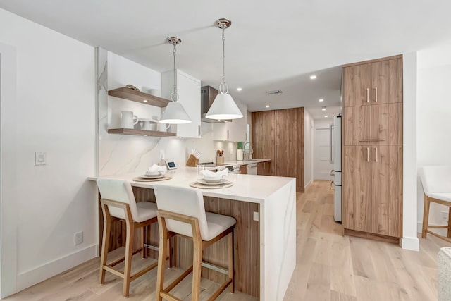 kitchen with a kitchen bar, kitchen peninsula, light hardwood / wood-style floors, and white appliances