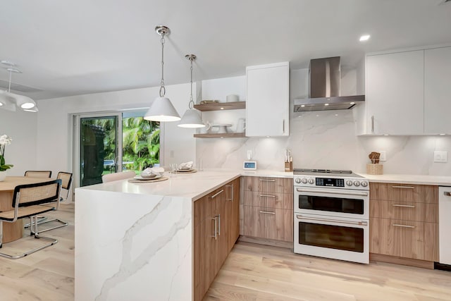 kitchen featuring light hardwood / wood-style floors, wall chimney range hood, white cabinetry, and stainless steel range oven