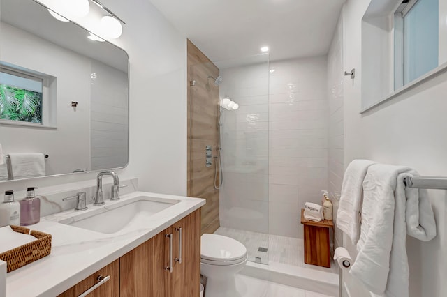 bathroom featuring toilet, vanity, and a tile shower