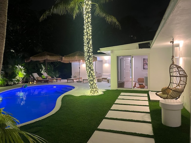 pool at twilight featuring a patio and a yard