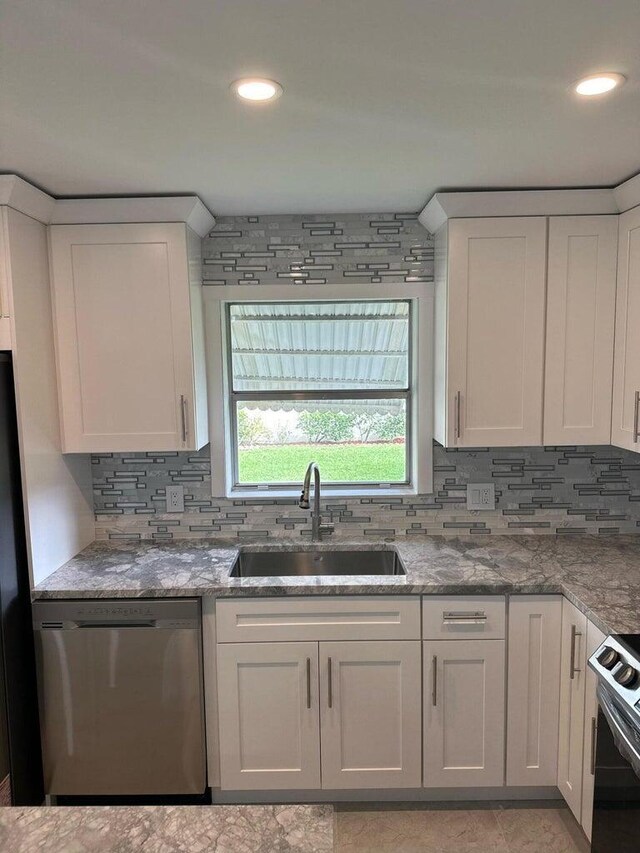 kitchen with tasteful backsplash, white cabinetry, sink, and stainless steel appliances