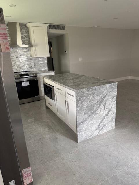 kitchen featuring white cabinets, stainless steel range with electric stovetop, wall chimney exhaust hood, and built in microwave