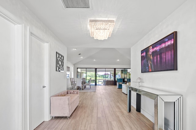 corridor featuring an inviting chandelier and light hardwood / wood-style flooring