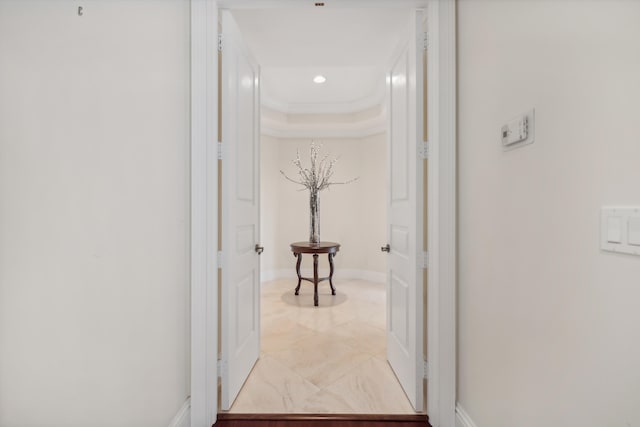 hallway featuring a raised ceiling and ornamental molding