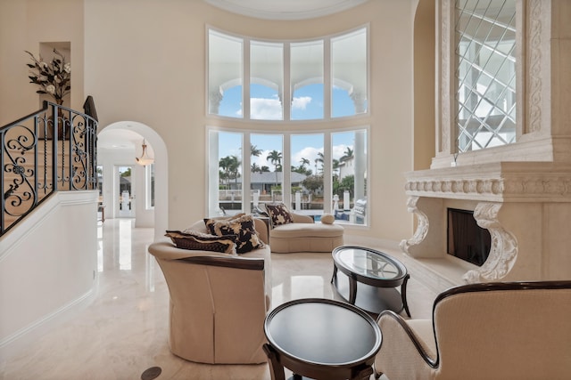 living room featuring a towering ceiling and a high end fireplace