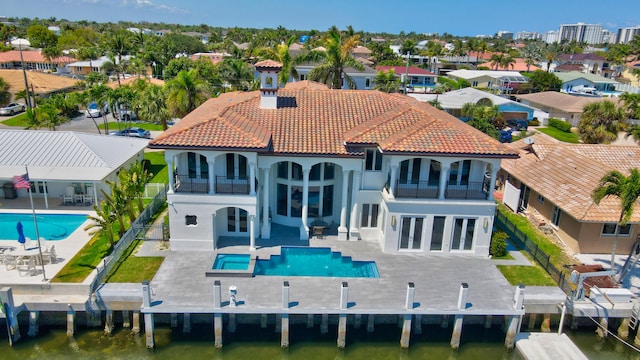 rear view of house with a balcony, a water view, a swimming pool with hot tub, and a patio area