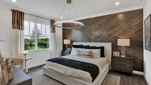 bedroom with ornamental molding, wooden walls, a notable chandelier, and dark hardwood / wood-style floors