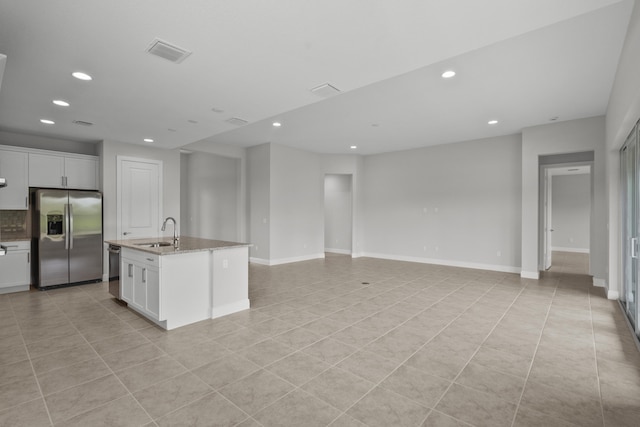 kitchen with white cabinets, stainless steel appliances, sink, and an island with sink