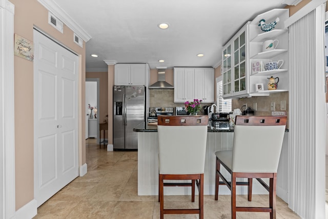 kitchen featuring white cabinets, wall chimney exhaust hood, decorative backsplash, and appliances with stainless steel finishes