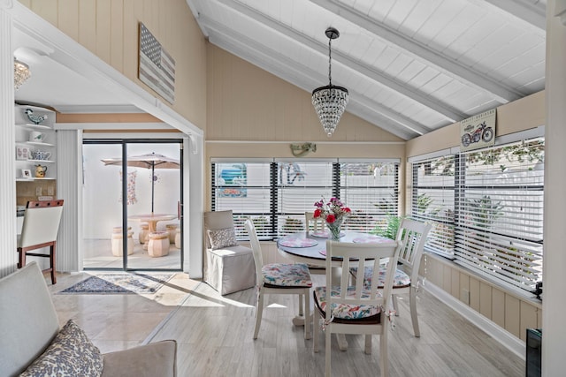 sunroom / solarium featuring lofted ceiling with beams and a notable chandelier