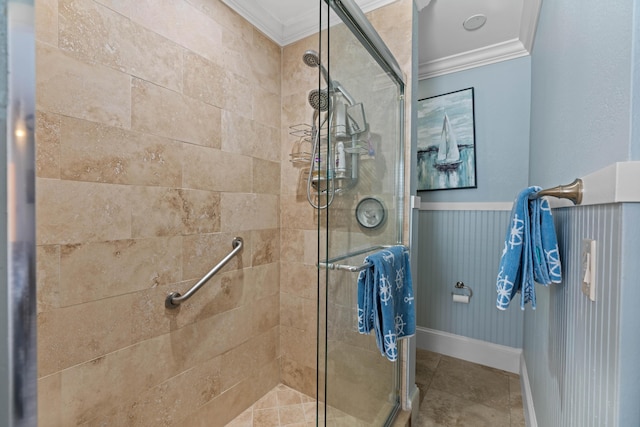 full bath featuring a wainscoted wall, ornamental molding, a shower stall, and tile patterned floors